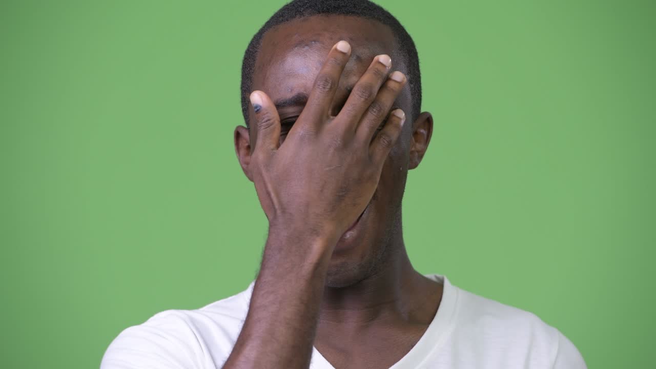Young African man shocked while covering face
