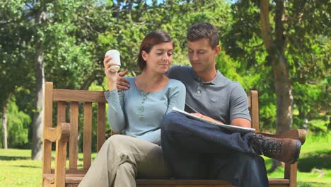 una pareja joven mirando un periódico.