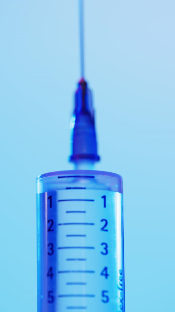 Vertical video of laboratory syringe with copy space on blue background