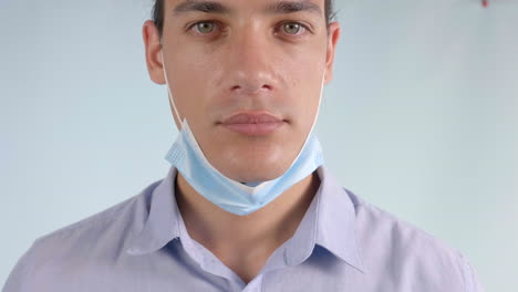 slow motion of a young man wearing a face mask below chin, closeup