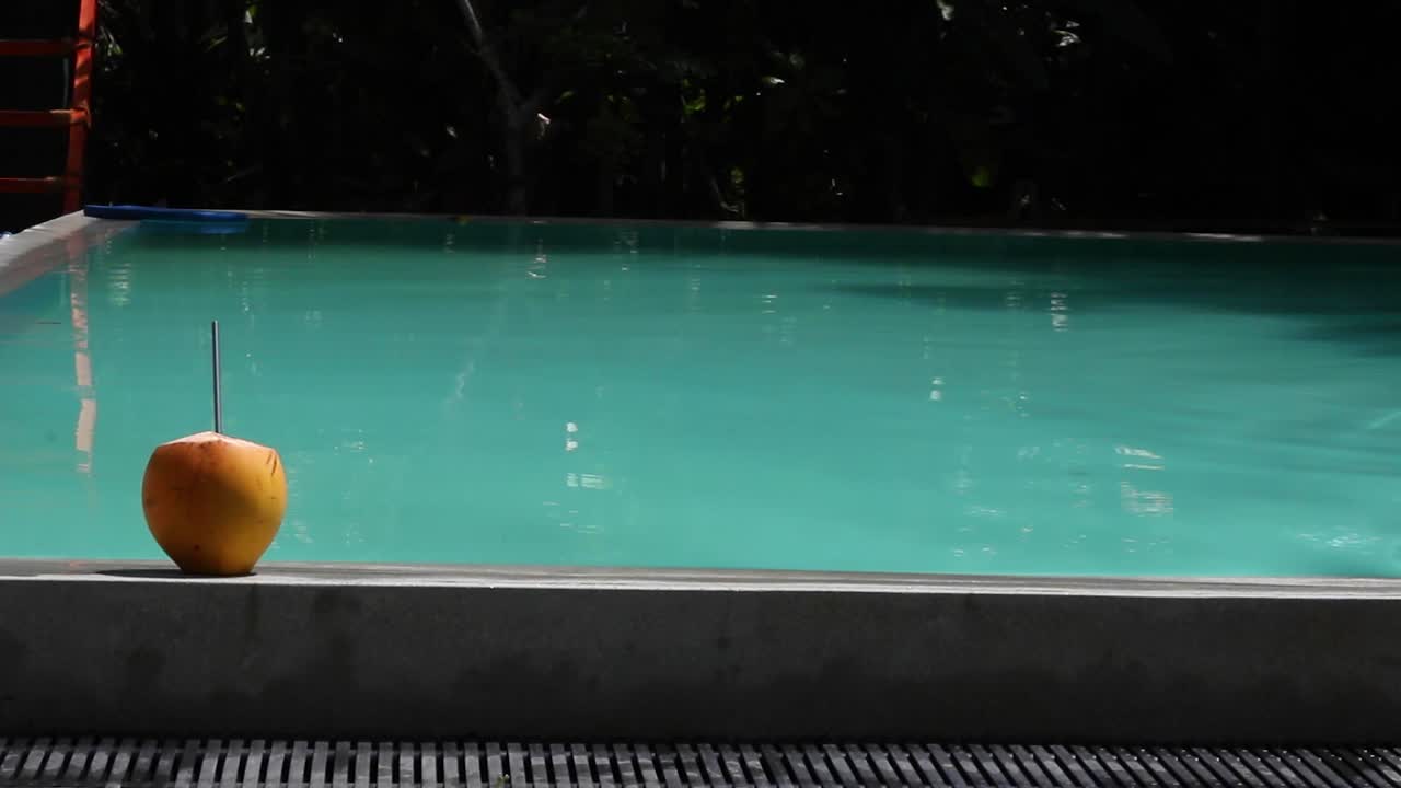 Kvinder går forbi en blå pool med kokosnødder ved siden af på et luksuriøst feriested