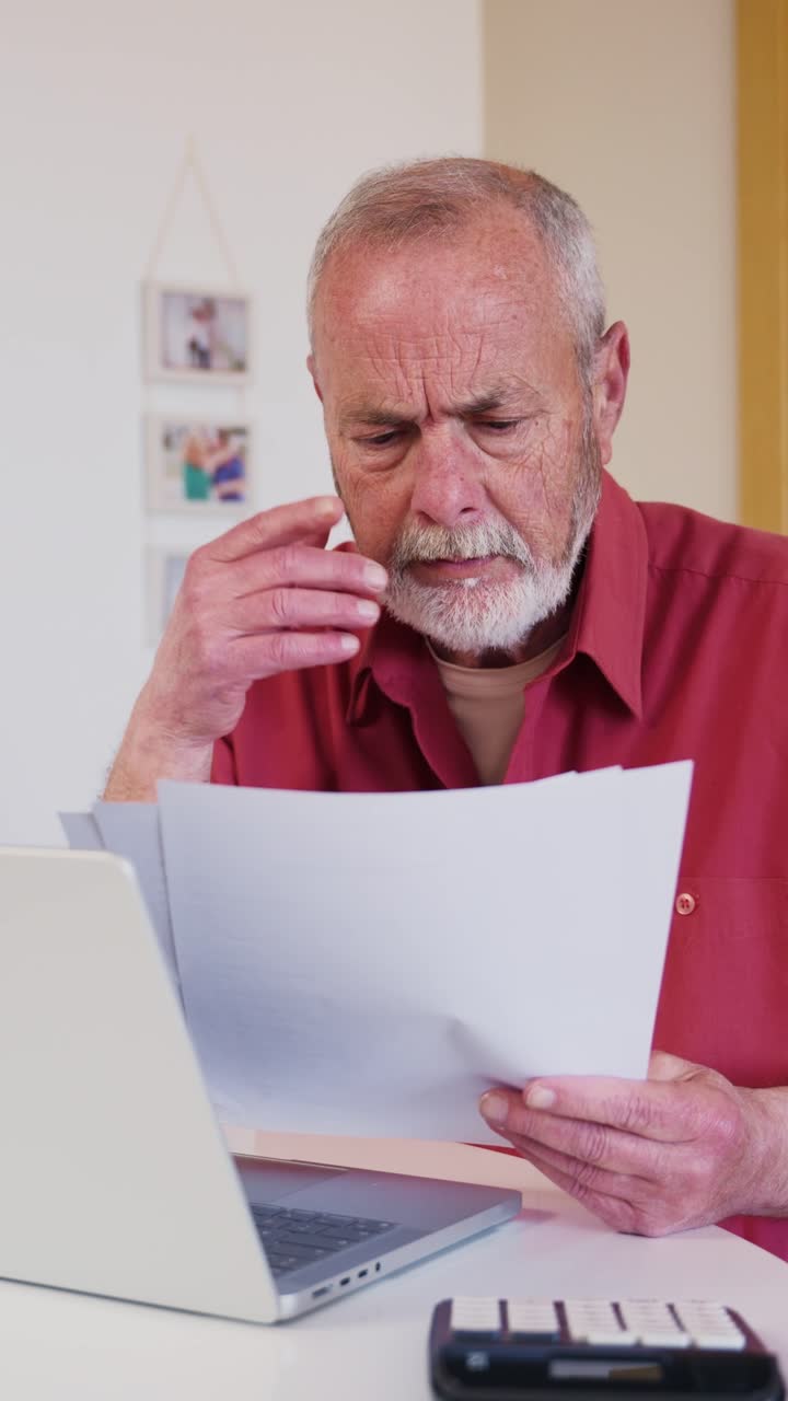 Hombre mayor preocupado leyendo documentos con portátil y calculadora
