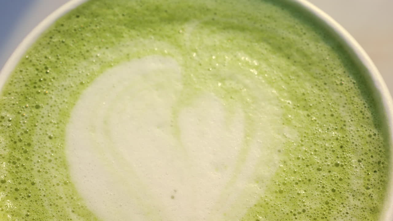 Foto macro da espuma de matcha latte com textura suave e cremosa e detalhes delicados de latte art.