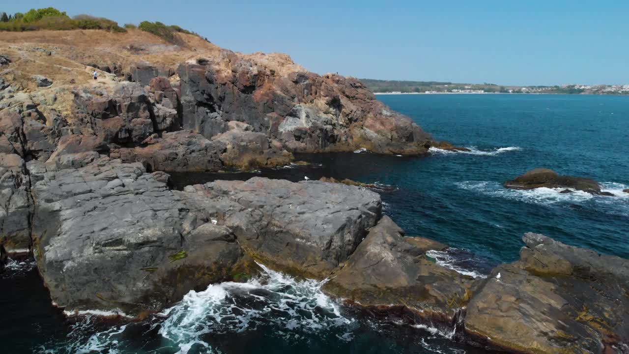 Aerial pan shot around big rocks in the sea and seagulls in sunny summer day