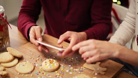 Tilt-down-view-of-couple-using-mobile-phone-at-Christmas