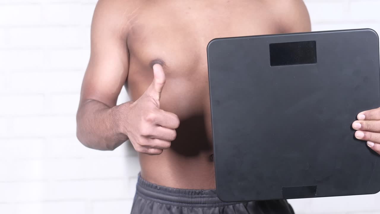 무게 척도를 들고 엄지손가락을 올리는 남자