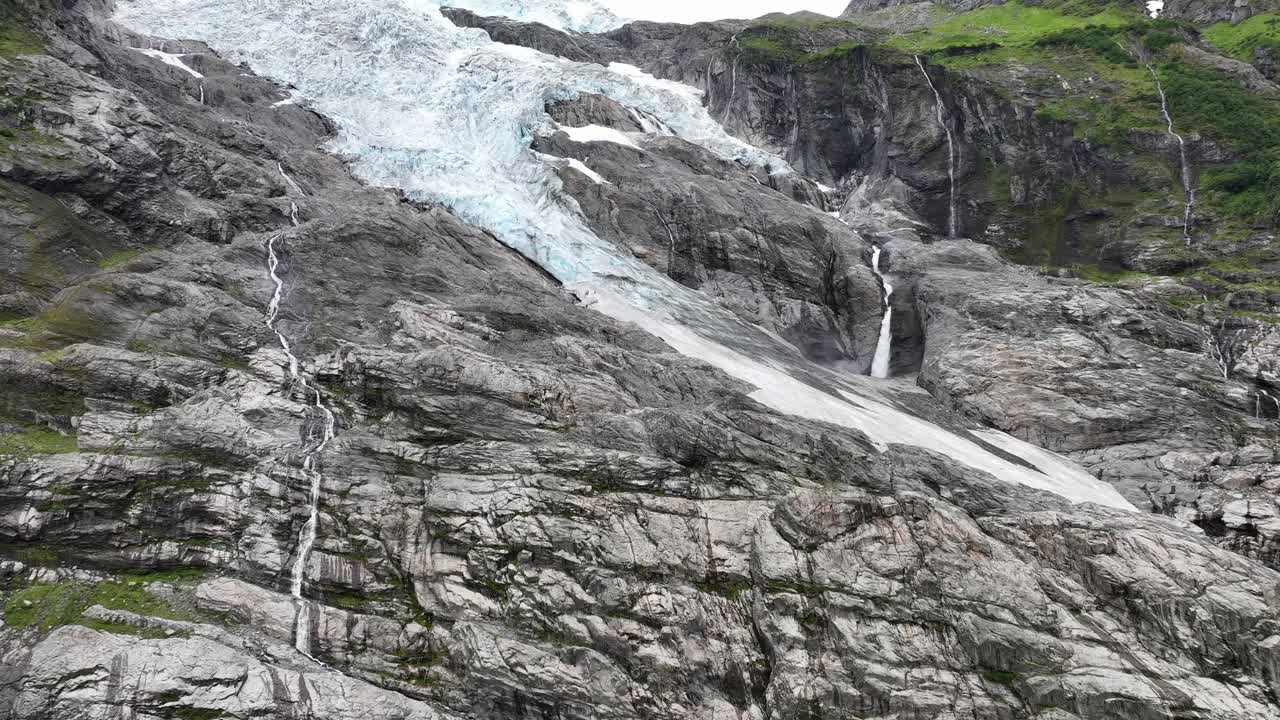 glaciar boyabreen - la lengua y el borde del glaciar jostedal en fjaerland noruega - movimiento aéreo hacia arriba revelando vista completa del glaciar con corriente de agua glacial derretida a la derecha - 60fps