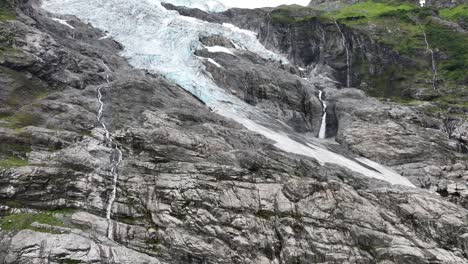 boyabreen glacier - the tongue and edge of the jostedal glacier in fjaerland norway - upward moving aerial revealing full glacier view with stream of melted glacial water to the right - 60fps