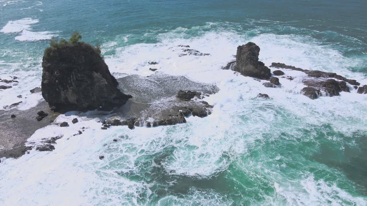 Ombak Putih Berbusa Menghantam Pulau Berbatu di Pesisir Watu Lumbung, Indonesia
