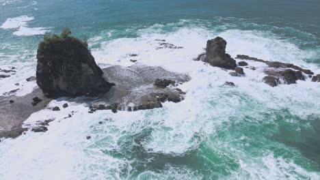 White-foaming-waves-crash-over-a-rocky-island-on-the-coast-of-Watu-Lumbung-in-Indonesia