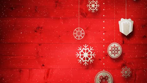 Animation-of-snow-falling-against-christmas-decoration-on-red-boards