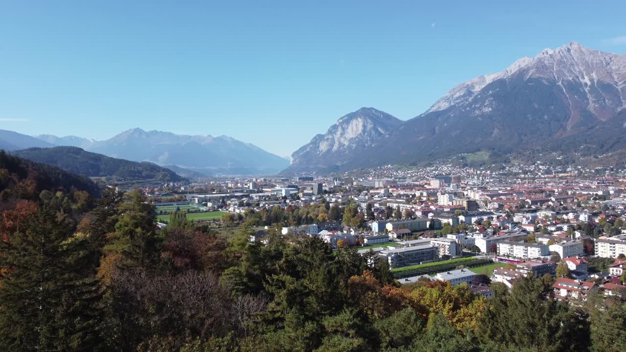 vista aérea de la ciudad de innsbruck desde las colinas de un bosque en un soleado día de otoño y un cielo azul y en el fondo los alpes, el tirol, austria, europa