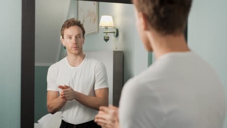 a handsome handsome guy applies hand cream in front of a mirror