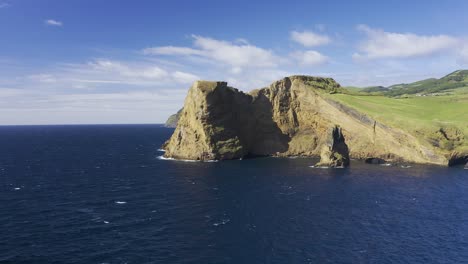 espectaculares acantilados volcánicos que revelan el pueblo de rosais, vegetación verde y formaciones de lava junto al metraje de drones marinos, isla de sao jorge, azores, portugal