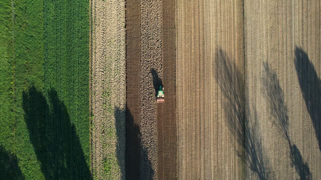 Vista aerea di un trattore agricolo con coltivatore per letto di semina su appezzamenti di terreno agricolo per la coltivazione, semina primaverile.