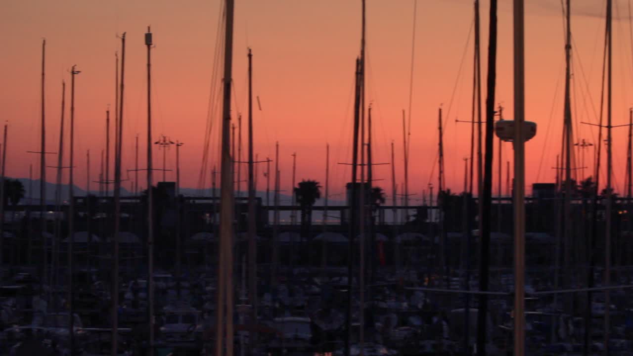 Silueta de yate con el fondo de una ciudad al atardecer. Paisaje de puerto de yates y mástil de barco.