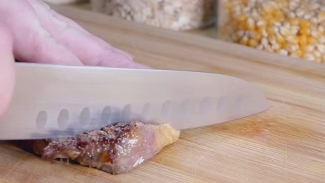 close slow motion slider shot of slicing a sirloin steak on a wooden chopping board