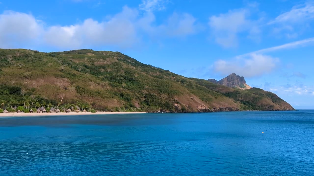 Vista panoramica delle Isole Yasawa nelle Fiji con spiaggia di sabbia bianca, ombrelloni e acqua blu dell'oceano in una popolare destinazione turistica nel Pacifico meridionale