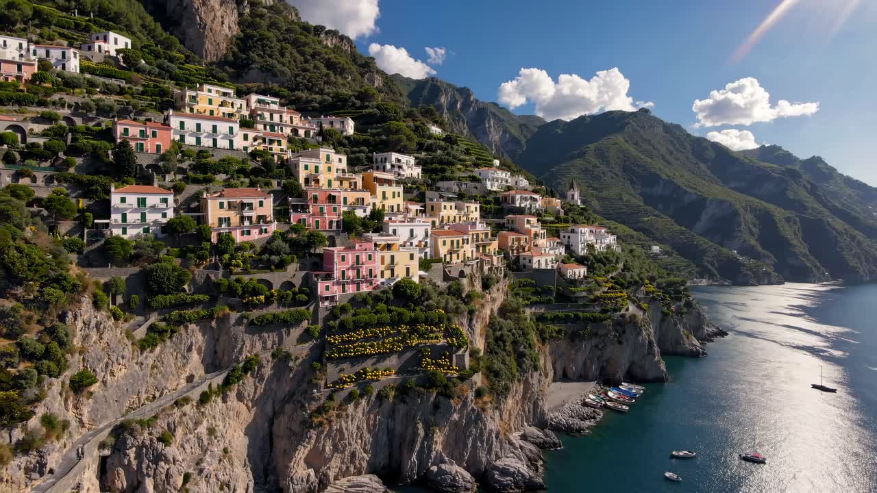 Aerial video captures vibrant cliffside village with colorful houses, lush greenery, and serene