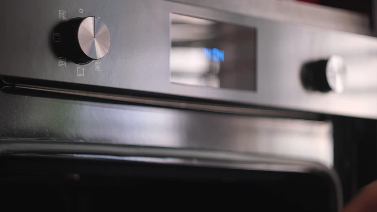 현대적인 오븐과 문을 열고 있는 사람