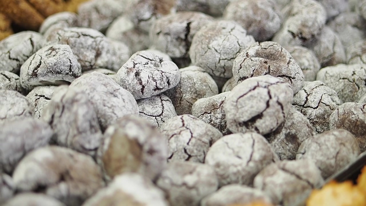 Primo piano di deliziosi biscotti al cioccolato crinkle coperti di zucchero a velo.