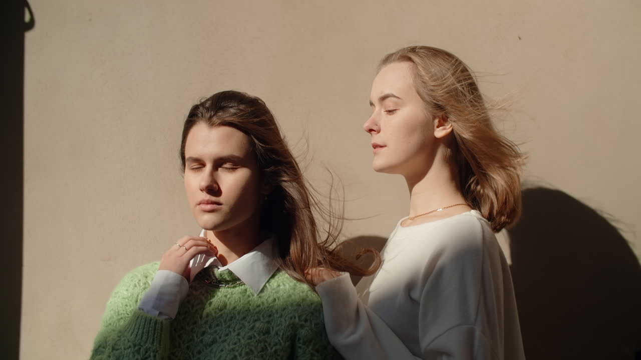 Two young women posing outdoors in sunlight