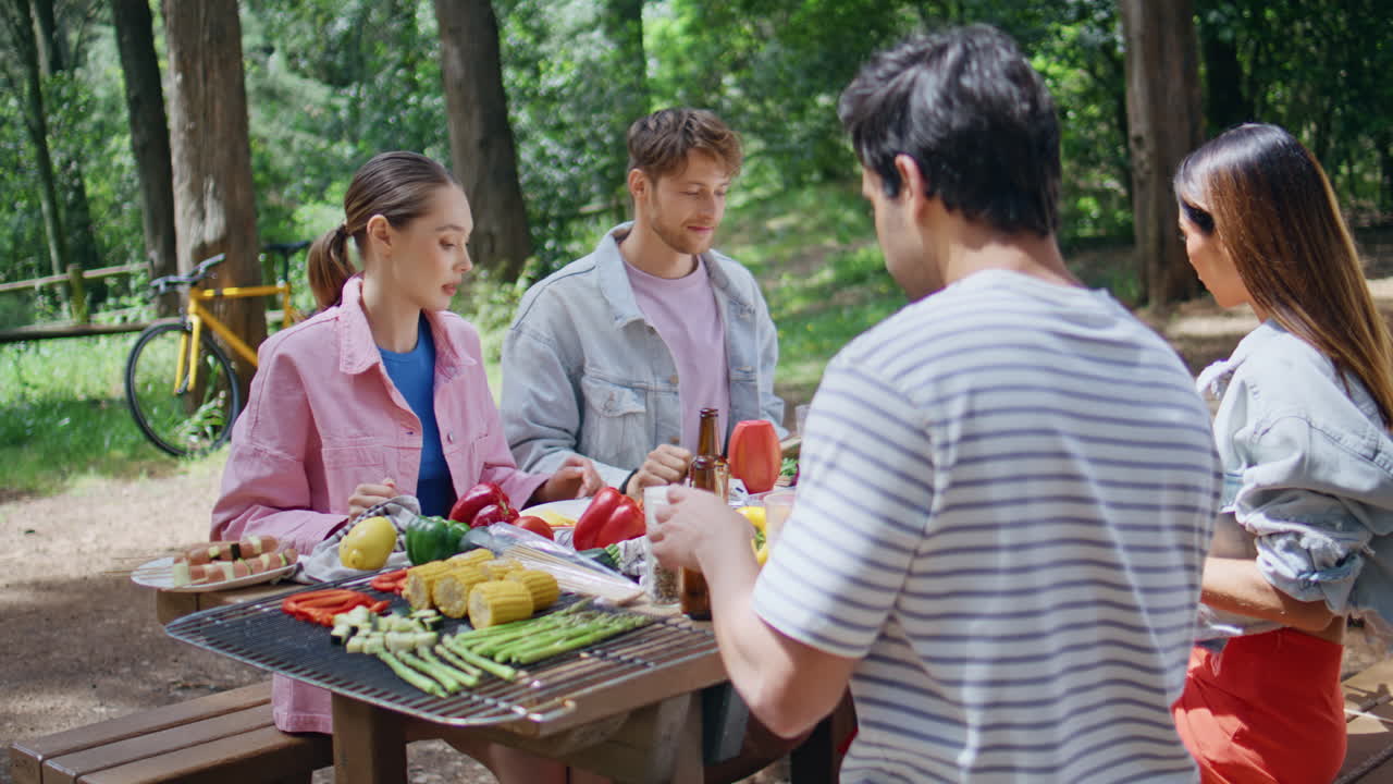 Friendly group having picnic in sunny forest closeup. Two young couple talking