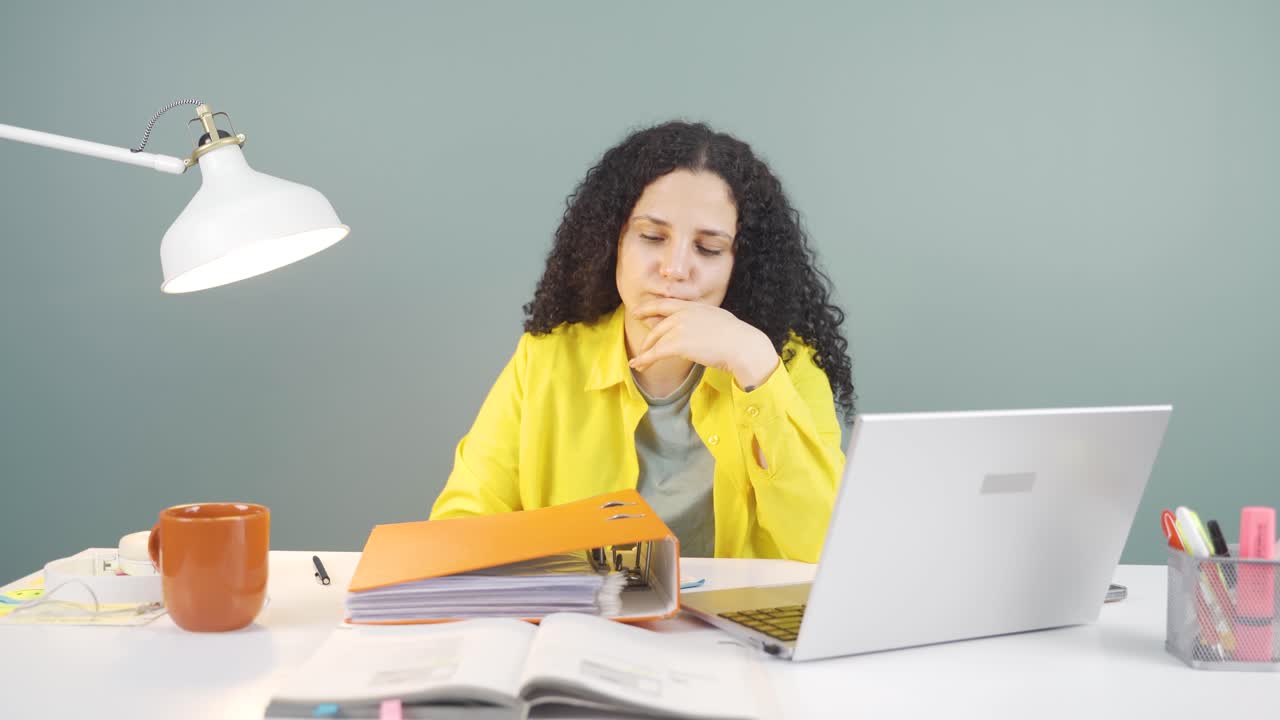 una joven que trabaja en una computadora portátil lanza archivos enojada.