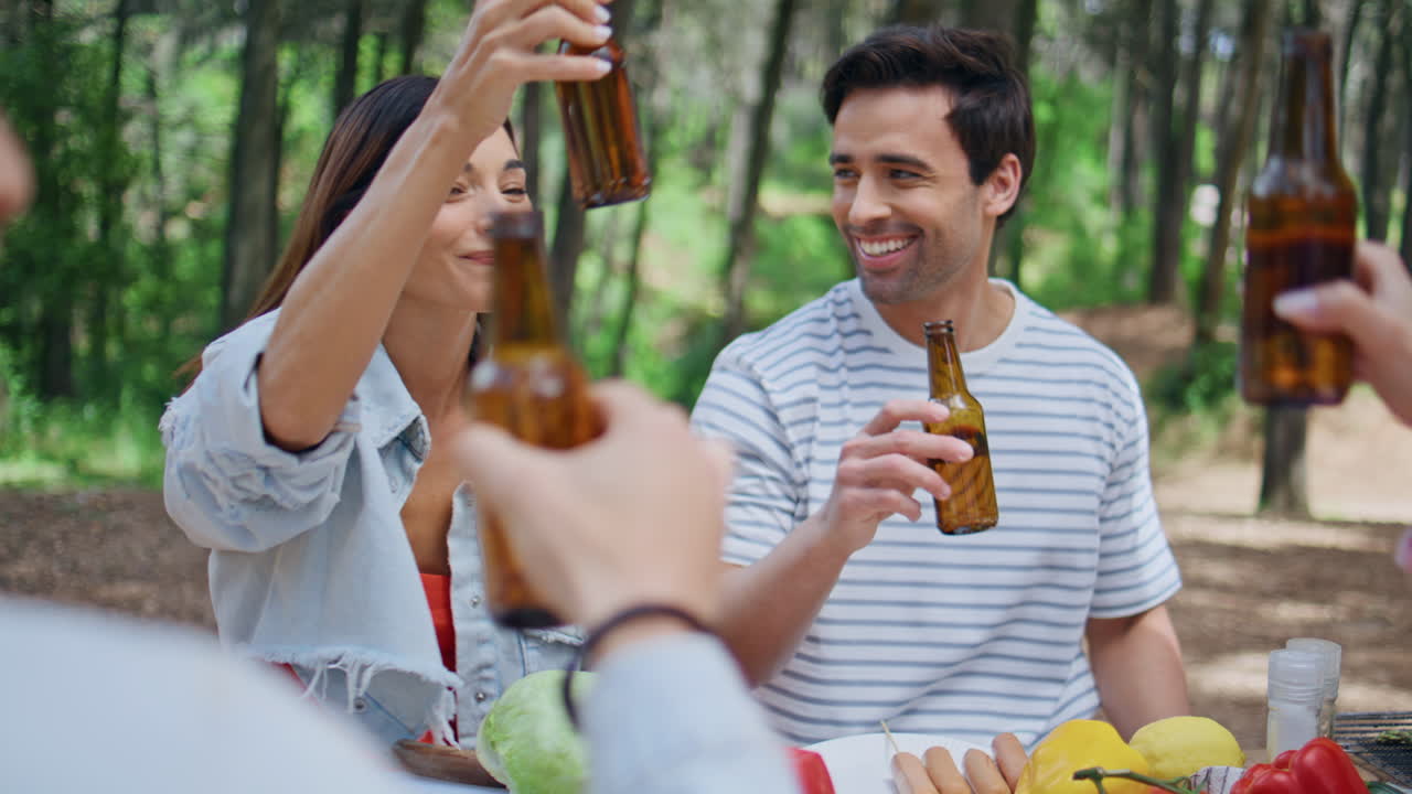Women men enjoying drinks food at forest picnic closeup. Happy friends toasting