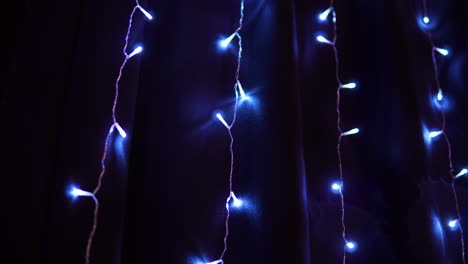 blue-colored fairy string lights glitter on the wall at dark