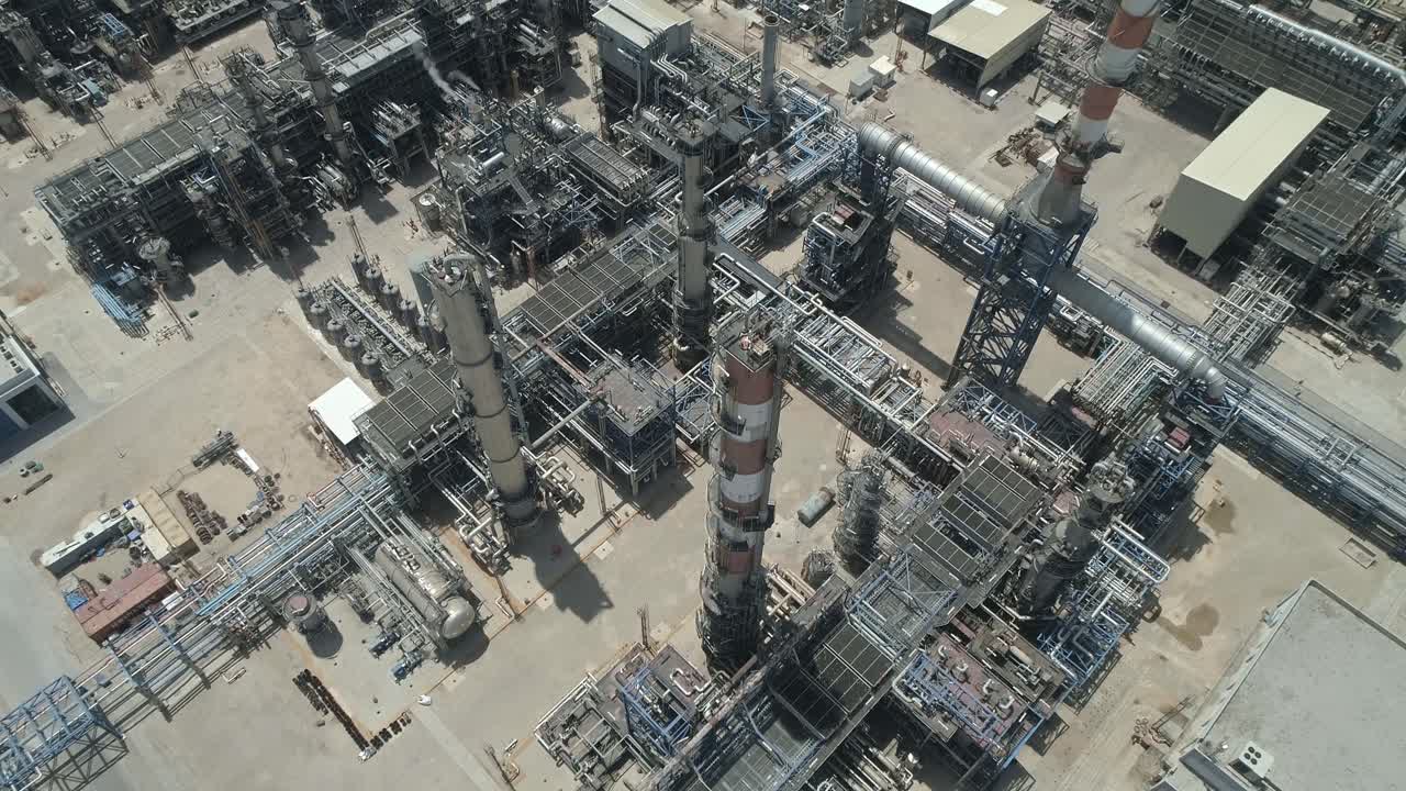 Aerial footage of a large scale Oil refinery with smoke stacks and petroleum storage tanks