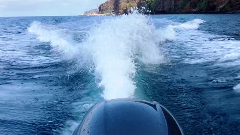 Splashing-Outboard-motor-speeding-through-the-blue-sea-waters-of-Madeira-island-surrounded-by-mountains--slow-motion