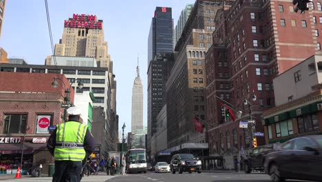 Un-Policía-De-La-Ciudad-De-Nueva-York-Dirige-El-Tráfico-Con-El-Empire-State-Building-Al-Fondo-1