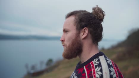 bearded norwegian guy drinking coffee outside looking at nature views