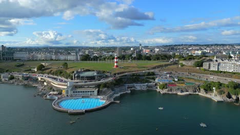 Un-Video-De-Dron-Volando-Hacia-Plymouth-Hoe,-Que-Muestra-El-Faro-De-La-Torre-De-Smeaton-Y-La-Piscina-De-Plymouth-Lido