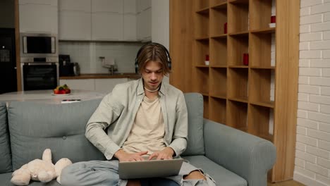 young man in headphones make video call using laptop sitting at home