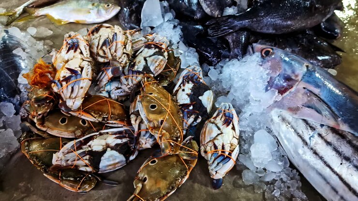Fresh blue swimmer crab and whole fish displayed on ice at a seafood market in Sri Lanka. Authentic coastal fishing industry scene with local trade and ocean harvest culture