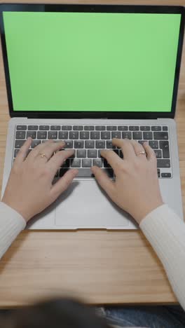 hands typing on laptop with green screen