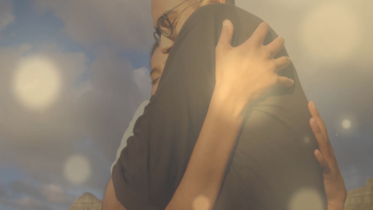 구름 인 하늘 배경에서 가운 보케 애니메이션으로 포옹하는 사람들