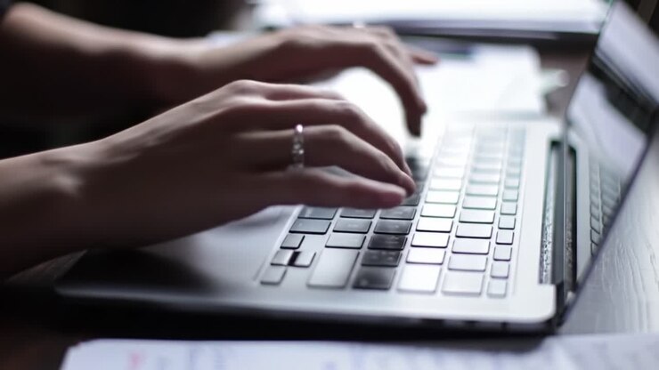 Focused Hands Typing on a Laptop Keyboard in a Cozy Workspace, Reflecting Modern Productivity and Digital Connectivity in the Contemporary World