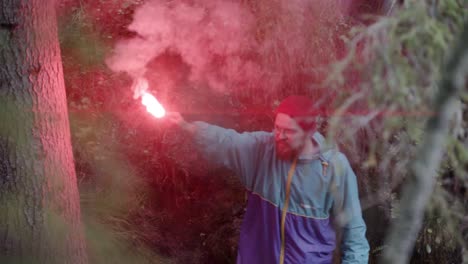 man with red smoke flare in forest