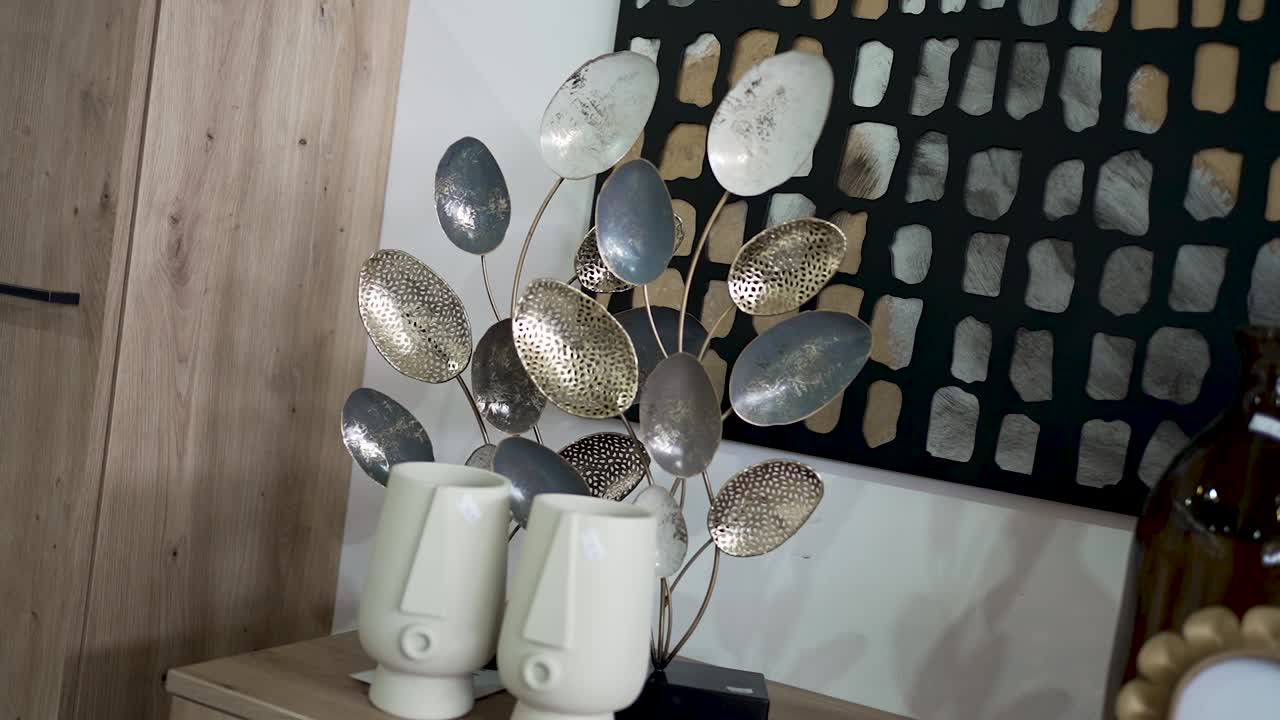Explore a stylish arrangement featuring a decorative metal sculpture with leaves and unique vases showcasing modern aesthetics in an elegant interior setting