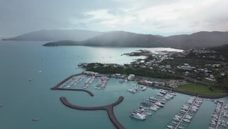 port airlie beach bay lagoon coral sea marina aerial drone rain clouds mist sunrise morning heart of great barrier reef whitsundays whitehaven jetty yachts sailboats buildings cars forward reveal