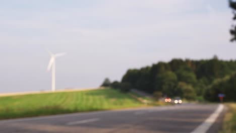 blurry view of cars driving road, windmill in background, copy space for titles