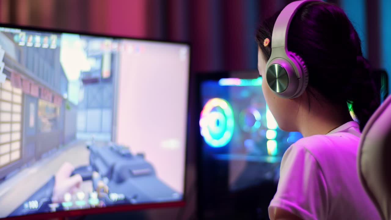 primer plano de una adolescente asiática emocionada que celebra la victoria y baila mientras juega a videojuegos en la computadora, videojuegos de disparos en línea