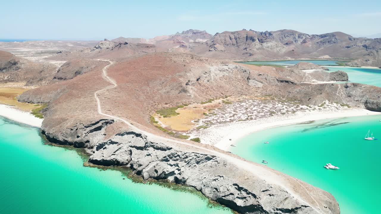 Remote beach cove in Tecolandra, La Paz with turquoise water and anchored boats