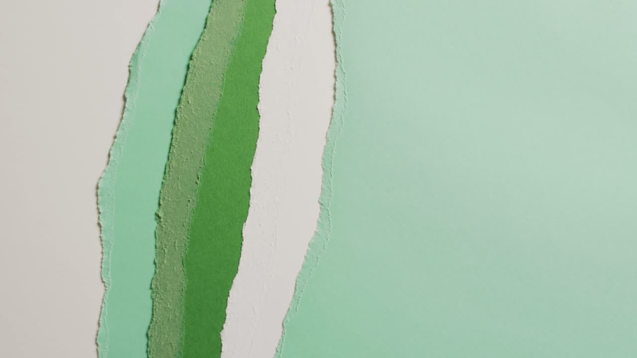 Video in primo piano di pezzi strappati di carta verde e bianca come sfondo.