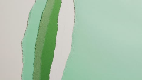 Video-of-close-up-of-torn-pieces-of-green-and-white-paper-background