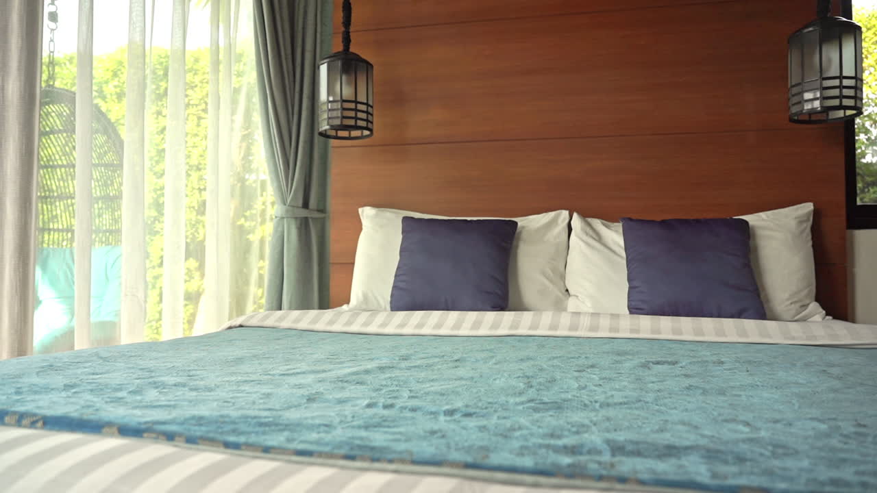 toma panorámica de izquierda a derecha en una habitación de hotel moderna con manta verde esmeralda, almohadas blancas y sábanas blancas a rayas