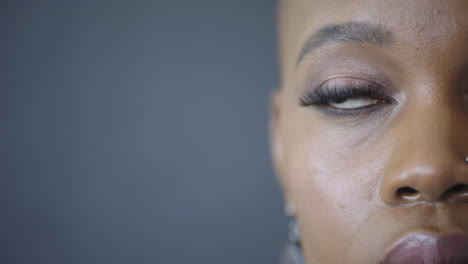 retrato en primer plano de una atractiva mujer afroamericana mirando a la cámara pensativa contemplativa belleza femenina negra sobre fondo azul mitad de la cara